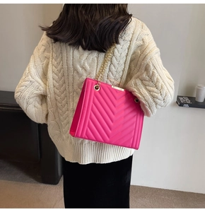 Close-up of rose pink chevron quilted crossbody bag with gold chain strap on model