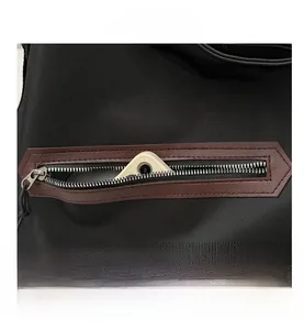 Close-up of black canvas bag featuring a metal zipper pocket with brown leather trim