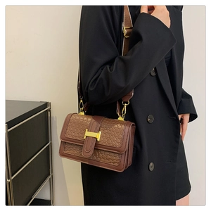 Détail du sac bandoulière tissé marron avec boucle métallique dorée en forme de H