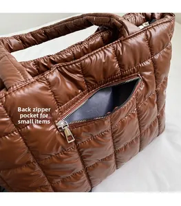 Detail view of the back zipper pocket on the brown quilted puffer tote bag for small items