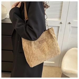 Detailed close-up of khaki corduroy tote bag with fashion tag and leather chain strap