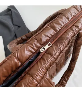 Detail of silver smooth metal zipper on brown quilted puff shoulder bag
