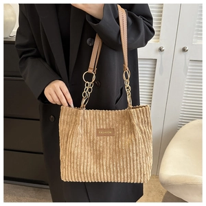 Detailed close-up of khaki corduroy tote bag showing metal fashion label and chain handle