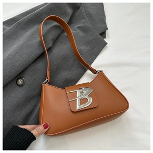 Dettaglio del logo B argentato e fibbia a rondine su borsa baguette marrone
