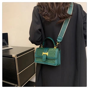 Détail du sac bandoulière tressé vert avec boucle en H dorée et bandoulière en toile