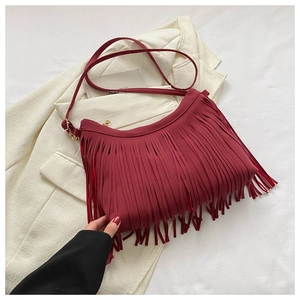 Detailed close-up of dark red fringe shoulder bag with bohemian tassels and gold hardware