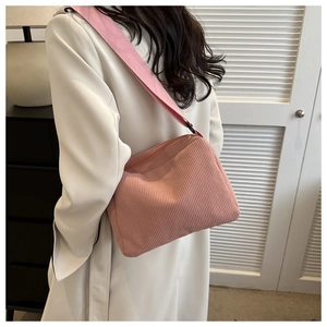 Detail of pink corduroy crossbody bag featuring soft ribbed texture and matching wide strap