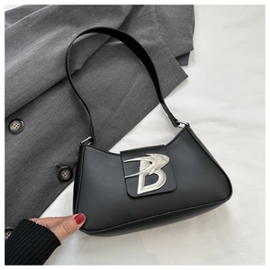 Dettaglio borsa baguette nera opaca con chiusura distintiva in metallo argentato logo B