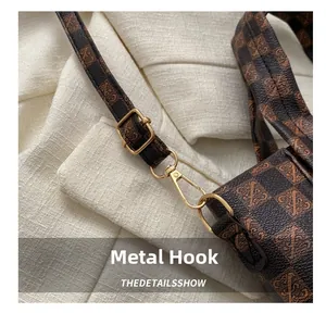 Detail of vintage checkered shoulder strap with golden metal hook and logo texture