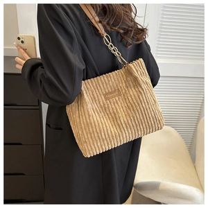 Close-up of brown corduroy tote bag with vertical stripes and metallic chain shoulder strap