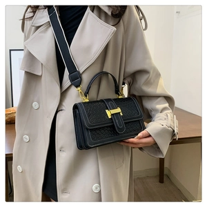 Détail du rabat en texture tressée noire et boucle dorée sur ce sac bandoulière