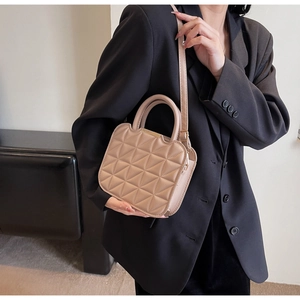 Dettaglio borsa in pelle beige trapuntata con manico rotondo e tracolla regolabile