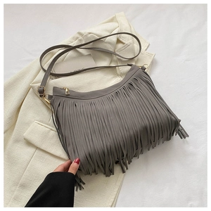 Detailed view of grey suede bucket bag with long fringe tassels on white blazer background