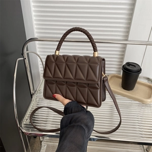 Chocolate quilted crossbody bag with woven handle and gold hardware in urban setting