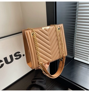 Detailed close-up of brown quilted faux leather bag with elegant gold chain strap