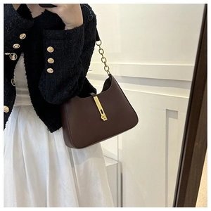 Sac hobo chic en cuir bordeaux foncé avec fermoir doré porté par un mannequin femme