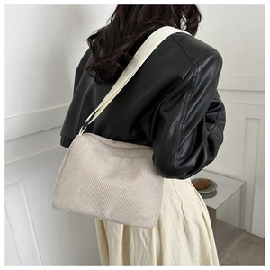 Detailed texture of off-white corduroy tote bag with wide strap on model's shoulder