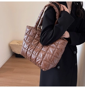 Brown quilted puffer tote bag shown on a model for a stylish large capacity shoulder look