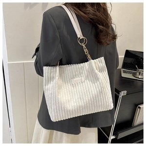 Detail of white corduroy tote bag featuring golden chain strap and fashion logo patch