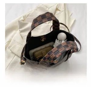 Top view of spacious vintage checkered bucket bag containing umbrella, wallet and tablet