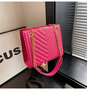 Close-up of rose red quilted crossbody bag with golden chain strap and leather shoulder pad