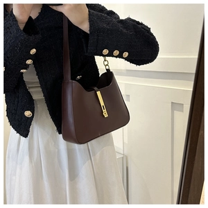 Close-up of deep brown leather crossbody bag with minimalist gold clasp on model