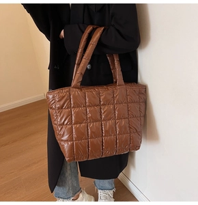 Detail of warm brown puffer tote bag with glossy quilted fabric and padded handles