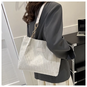 Close-up of beige corduroy tote bag showing metal ring strap and fashion leather patch