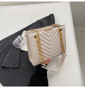 Detail of cream-colored crossbody bag with V-quilted stitching and gold chain strap