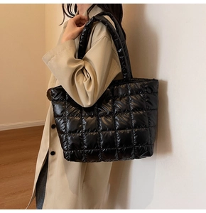Detail of black quilted puffer tote bag with glossy finish and soft padded shoulder straps