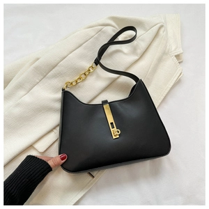 Detail of minimalist black leather bag with gold metal clasp and chunky chain strap