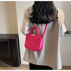 Dettaglio borsa trapuntata rosa con fibbia dorata abbinata a un blazer beige