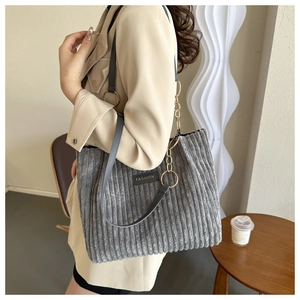 Detail of gray corduroy tote bag with Fashion label and leather chain strap shown on model