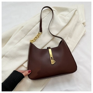 Detail of dark brown leather underarm bag with gold metal lock and elegant chain strap