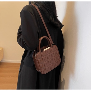 Borsa a tracolla marrone trapuntata abbinata a un cappotto nero per uno stile invernale alla moda