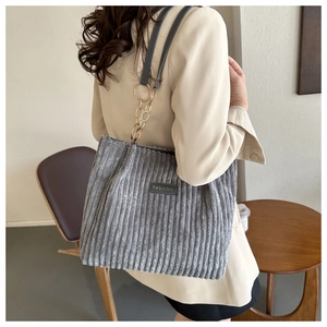 Detail of grey corduroy tote bag with dual metal chain and black leather straps