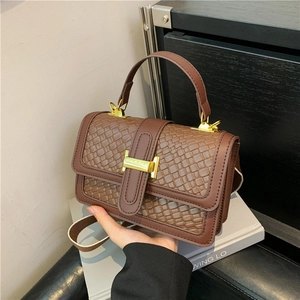 Sac à main marron à motif tissé avec boucle en H dorée présenté dans un décor de vie