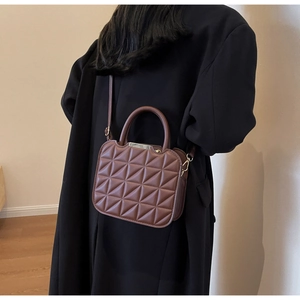 Dettaglio di una borsa quadrata marrone trapuntata con motivi geometrici e manico