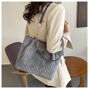 Detail of grey corduroy tote bag featuring metal ring chain strap and fashion label