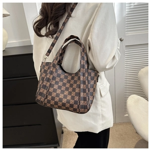 Detail view of coffee-colored checkered handbag with top handles and adjustable strap