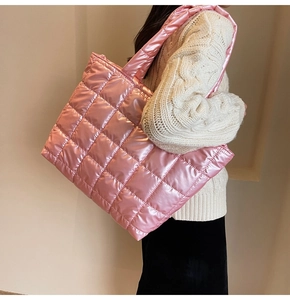 Side view of pink quilted puffer tote bag with glossy finish on female model