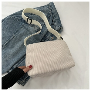 Close-up of white corduroy crossbody bag with adjustable wide canvas shoulder strap
