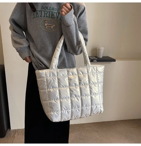Detail of white quilted puffer tote bag with glossy finish on a shoulder strap view