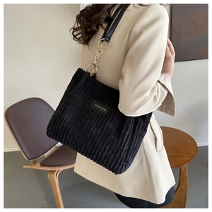 Detail of black corduroy tote with leather strap and gold chain ring connector