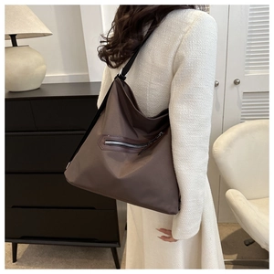 Close-up of brown large capacity tote bag with front zipper pocket on a model