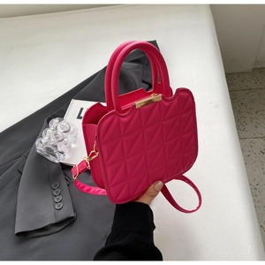 Dettaglio ravvicinato della borsa fucsia trapuntata con manico dorato e motivo a rombi