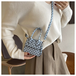 Close-up of mini light blue crossbody bag with black geometric patterns on a casual model