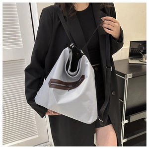 Detailed shot of large grey tote bag with brown zipper trim and black adjustable strap