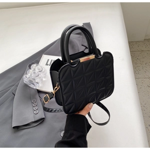 Dettaglio borsa nera goffrata con bordo dorato ondulato e manico rotondo elegante