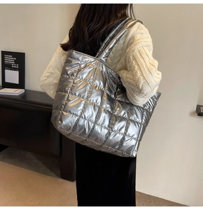Detail of silver quilted puffer tote bag with glossy metallic finish and shoulder straps
